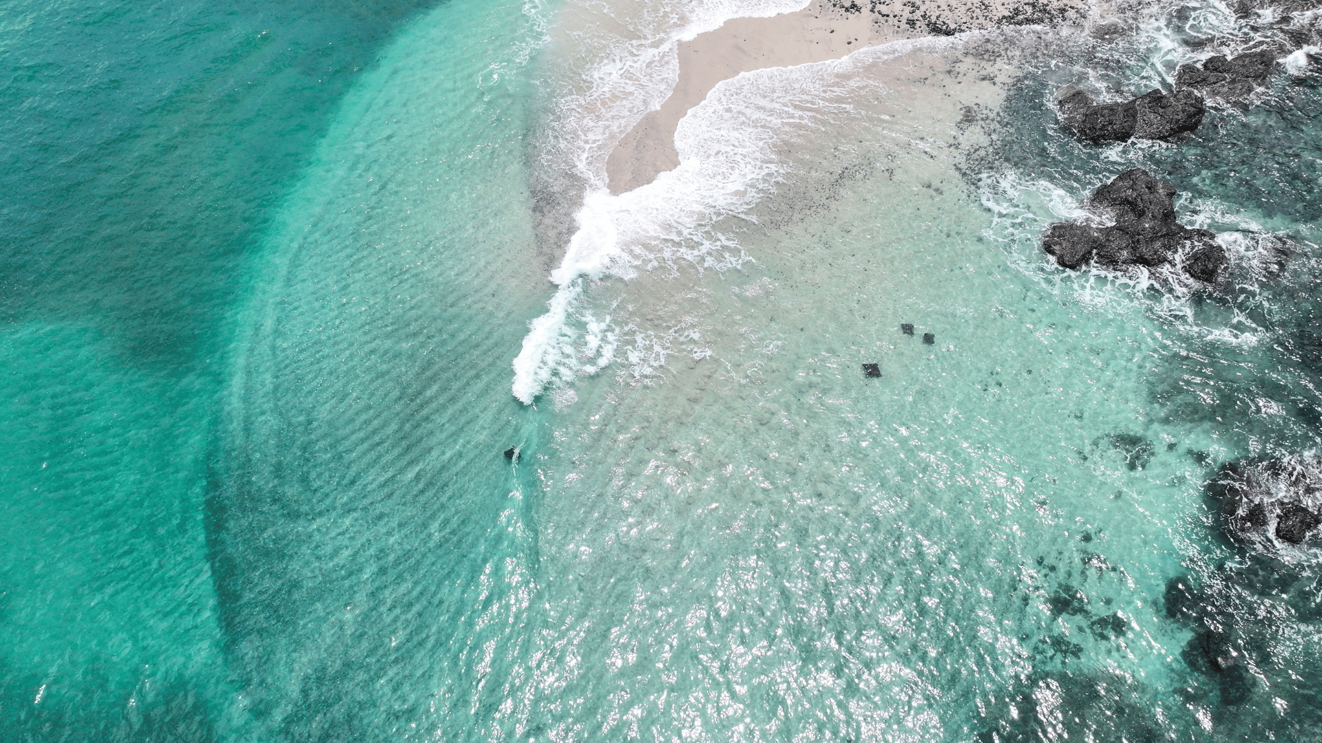 Surfers riding waves at Guiones Beach with lush green hills along the coastline