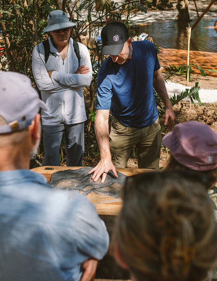 Group gathered around a wooden table reviewing a topographical map outdoors